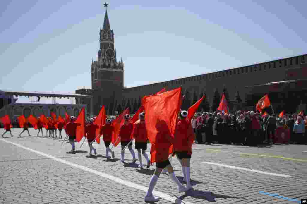 Дети маршируют с красными флагами без какой-либо символики перед Спасской башней Кремля. Инициатива Коммунистической партии РФ появилась в то время, когда детей в школах по всей России принуждали к демонстрации &laquo;поддержки&raquo; вторжения в Украину, часто без ведома родителей