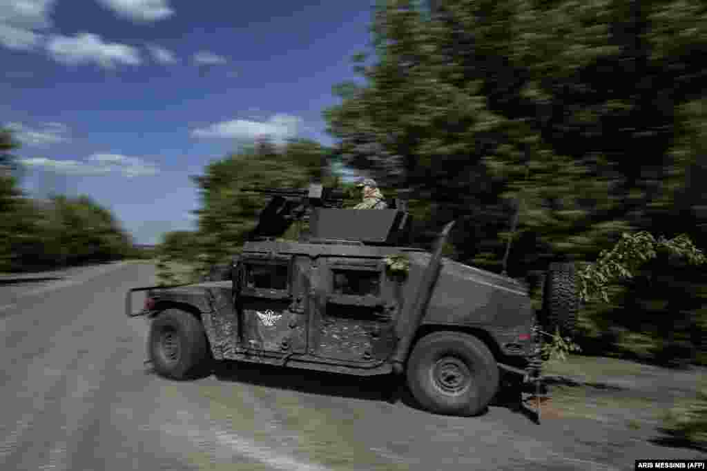 A Ukrainian serviceman sits atop a Humvee produced in the United States as they race toward the front line. Washington has sent hundreds of Humvees to the Ukrainian armed forces.