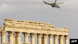 Syria -- A Russian Mil Mi-24 "Hind" attack helicopter flies above the damaged site of the ancient city of Palmyra, March 4, 2017
