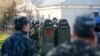 Naoružani muškarci, za koje se vjeruje da su ruski vojnici, čuvaju stražu, a ukrajinski vojnici viđeni su u prvom planu, u vojnoj zračnoj bazi, u krimskom gradu Belbek u blizini Sevastopolja, 22. marta 2014. 