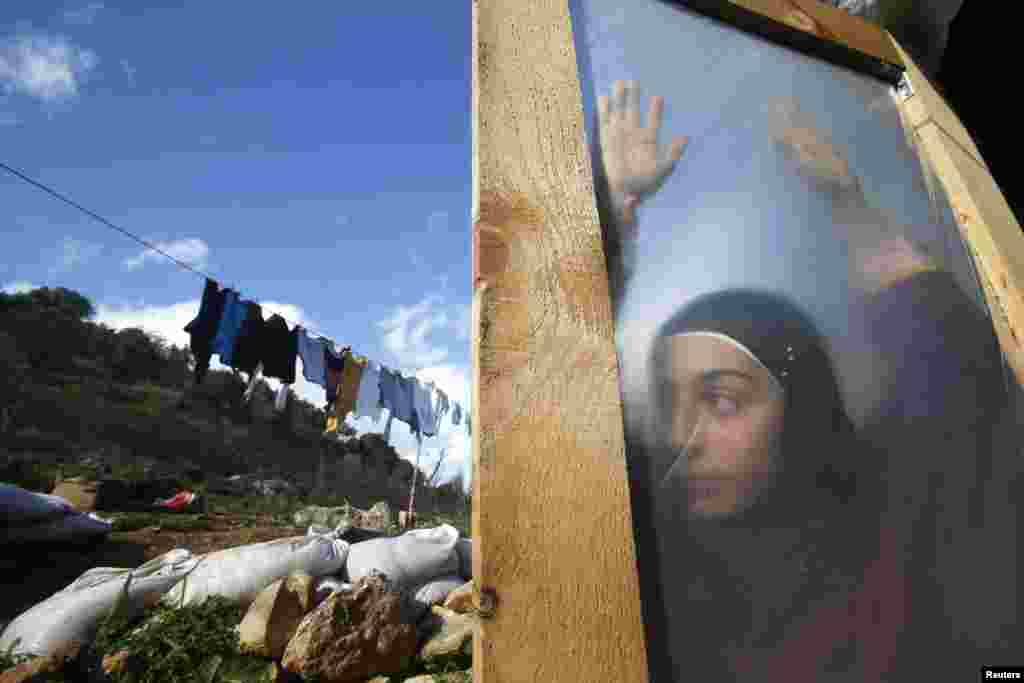 A Syrian refugee girl stands behind a door at a makeshift settlement in the village of Ketermaya, south of Beirut, Lebanon, January 8, 2015. Snowfall and gales in Lebanon&#39;s Bekaa Valley destroyed some refugee tents. (Reuters/Ali Hashisho)