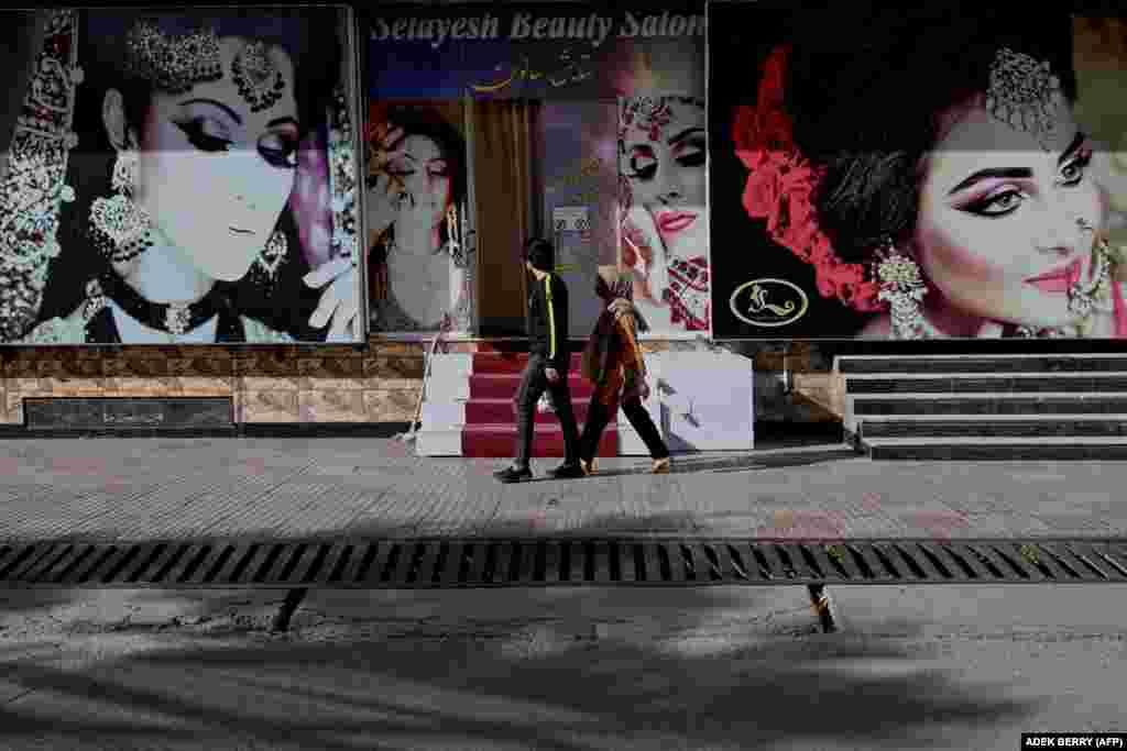 Një çift duke kaluar para hyrjes së një salloni bukurie, në Kabul. (10 qershor)