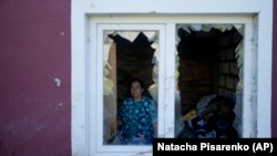 A woman looks out of her home, destroyed by attacks in Mostyshche, on the outskirts of Kyiv.