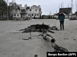 Një burrë duke shikuar tytën e një tanku të shkatërruar në Zalisja, një qytet në verilindje të Kievit, më 12 prill. Pjesë të tankut të shkatërruar ishin shpërndarë rreth 50 metra larg në anën tjetër të një autostrade.