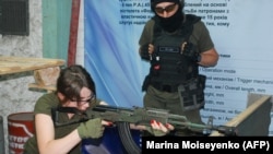 Një instruktor i mëson një vullnetareje se si të përdorë një armë të tipit Kallashnikov, më 17 qershor 2022, në Zaporizhzhia, Ukrainë.
