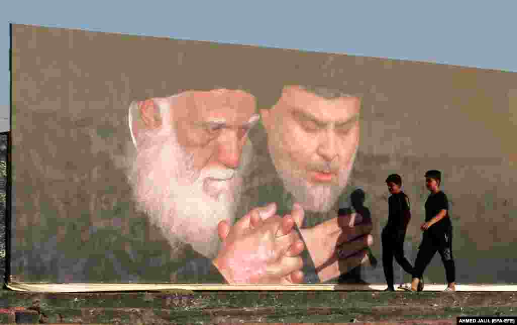 Two Iraqi boys pass by the pictures of Muqtada al-Sadr and his father, Mohamed Sadiq al-Sadr, in Sadr city, the stronghold of followers of the Sadrist Movement in northeastern Baghdad on June 14.