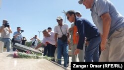 Булат Абилов (в темном), Рысбек Сарсенбайулы (слева от Абилова) и другие общественные деятели возлагают цветы у монумента на площади Республики в Алматы в память о погибших во время январских событий. 6 июля 2022 года