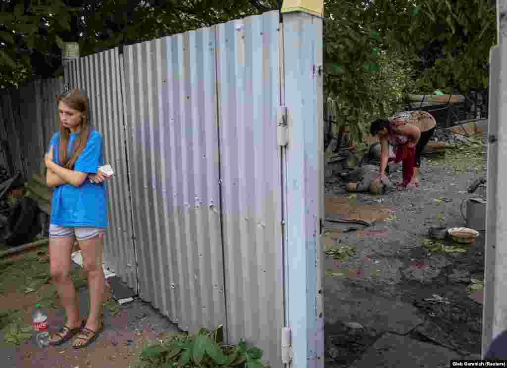 Devojka čeka dok žena miluje tijelo svoje svekrveubijene tokom ruskog vojnog napada na Kostjantjnivku 9. jula.