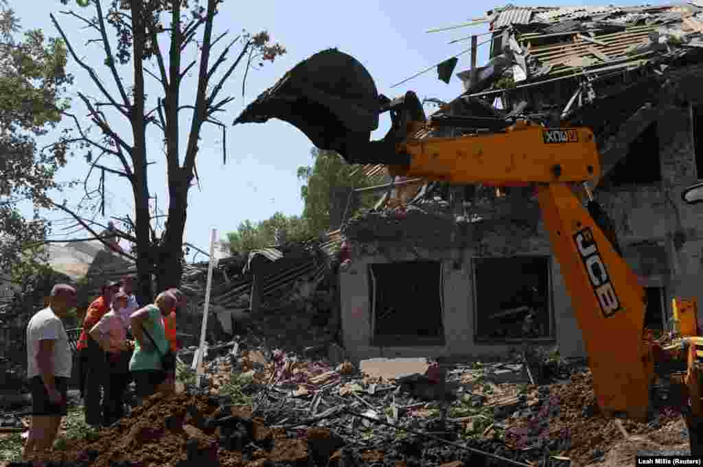 Bystanders watch as debris is removed from the destroyed Lyubotyn Vocational College of Railway Transport near Kharkiv on June 20. According to Ukrainska Pravda, two Russian cruise missiles struck the college, which also housed a volunteer center where people could collect humanitarian aid for internally displaced people.