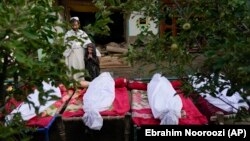 Afghans stand by the bodies of relatives killed in the earthquake in the village of Gayan in Paktika Province.