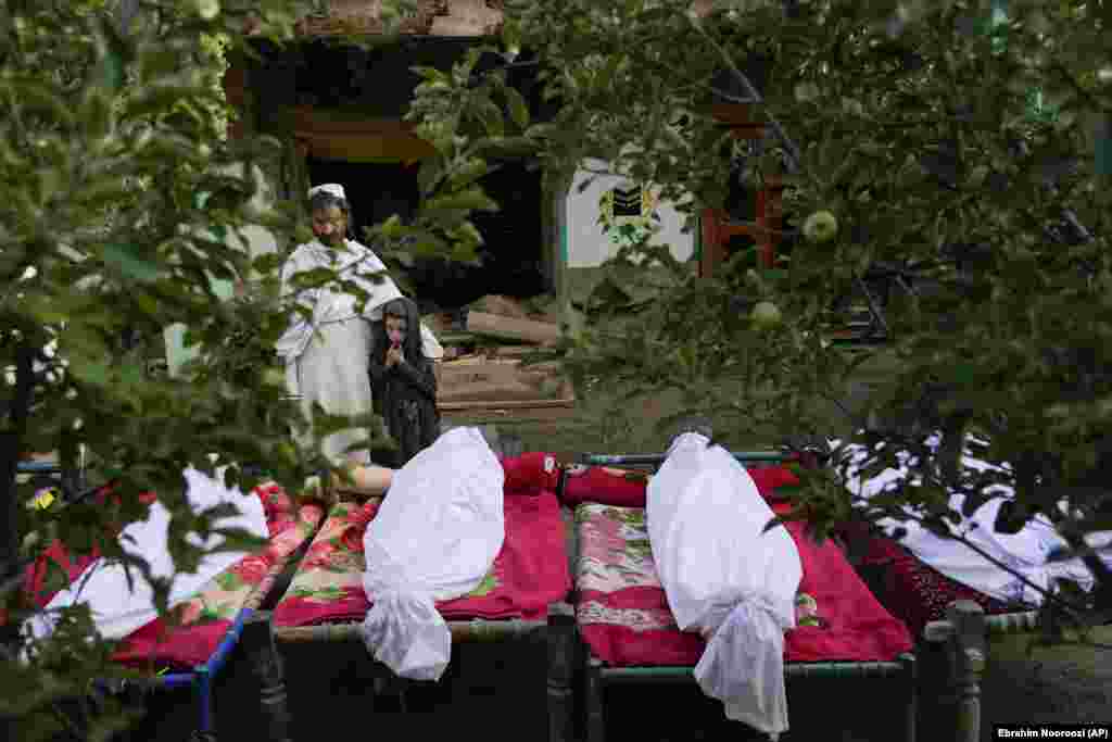 Afghans stand by the bodies of relatives killed in an earthquake in the village of Gayan in Paktika Province on June 23. At least 1,150 people were killed in the powerful June 22 earthquake.
