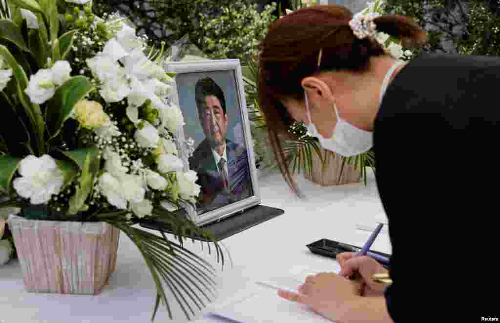 O japoneză scrie un mesaj de condoleanțe în fața unei fotografii&nbsp; a fostului prim-ministru japonez Shinzo Abe, plasată pe un altar la sediul Partidului Liberal Democrat&nbsp; în Tokyo, Japonia, 11 iulie 2022