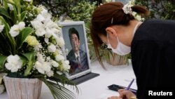 Një grua duke shkruar në librin e zisë për ish-kryeministrin japonez, Shinzo Abe. Tokio, 11 korrik 2022.
