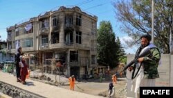 Taliban militants stand guard at the site of an explosion in front of a Sikh temple in Kabul on June 18. 