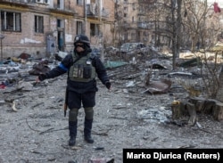 Një polic ukrainas në vendin ku ndodhi një shpërthim nga sulmet ruse në një zonë banimi në Kiev më 18 mars.