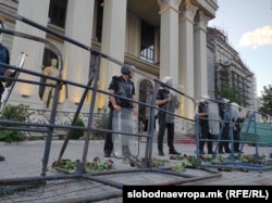 Police in riot gear stand guard against protesters, who threw roses at their feet.