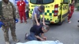 A Man is crying over a dead body in front of an ambulance In Kharkiv