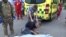 A Man is crying over a dead body in front of an ambulance In Kharkiv