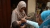 A health worker administers polio vaccine drops to a child during a door-to-door vaccination campaign at a slum area in Lahore on June 27.