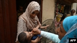 A health worker administers polio vaccine drops to a child during a door-to-door vaccination campaign at a slum area in Lahore on June 27.