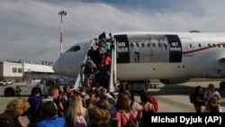 Ukrán menekültek várakoznak a beszállásra egy Kanadába tartó repülőgépre Varsóban 2022. július 5-én
