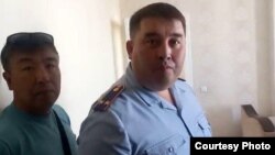 Подполковник Марат Дубаев (справа) в квартире, в которой жанаозенцы заночевали после того, как их задержали перед зданием министерства труда и доставили в полицию, чтобы наложить на них штрафы. Нур-Султан, 24 июня 2022 года