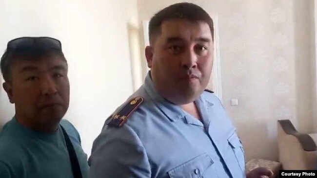 Подполковник Марат Дубаев (справа) в квартире, в которой жанаозенцы заночевали после того, как их задержали перед зданием министерства труда и доставили в полицию, чтобы наложить на них штрафы. Нур-Султан, 24 июня 2022 года