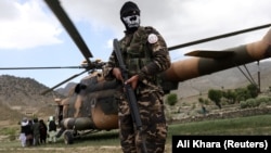 Egy tálib harcos őrködik egy helikopter mellett egy földrengés sújtotta területen, a délkelet-afganisztáni Paktika tartományban 2022 júniusában