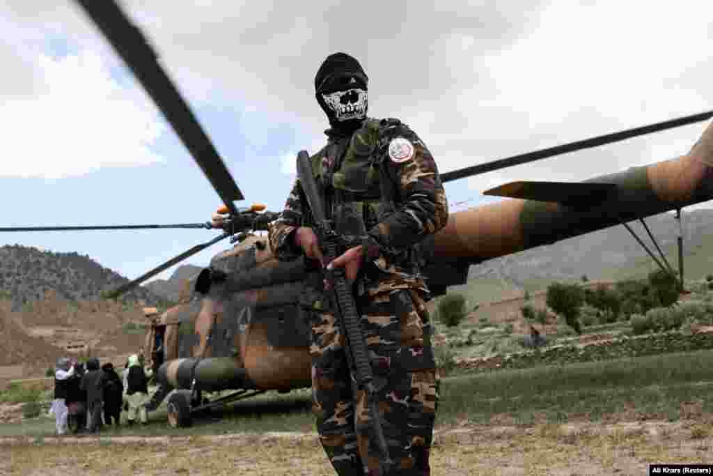An armed Taliban fighter guards a helicopter used to disperse aid and pick up injured survivors. The disaster is a major litmus test for the hard-line Islamists, who have been largely isolated and shunned by the international community over human rights concerns.