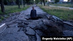 Viktor Sevcsenko egy lövedék ütötte kráterben áll egy orosz támadást követően az ukrajnai Harkiv Szaltivka negyedében 2022. július 1-jén 