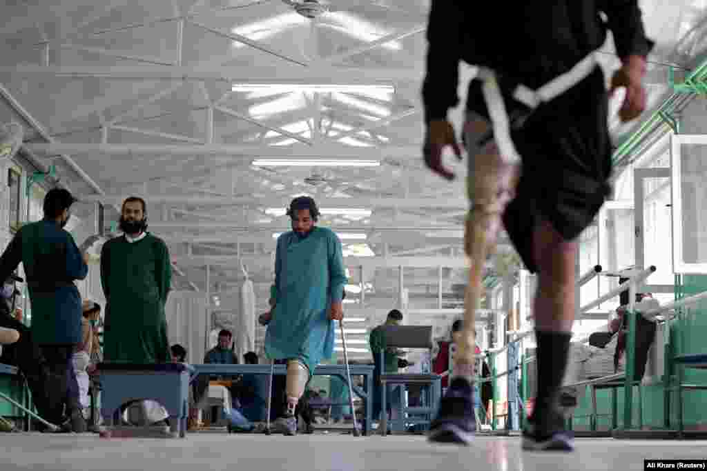 Mohammad Zahir (center), 34, who lost both legs in a mine blast in Kandahar, practices walking with a new prosthesis.&nbsp;Many of the staff members are amputees who have been trained to manufacture, fit, and provide physical therapy to other amputees.