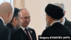  Vladimir Putin (centru) discutând cu președintele iranian Ebrahim Raisi, în timpul celui de-al 6-lea Summit Caspic la Ashgabat, la 29 iunie 2022