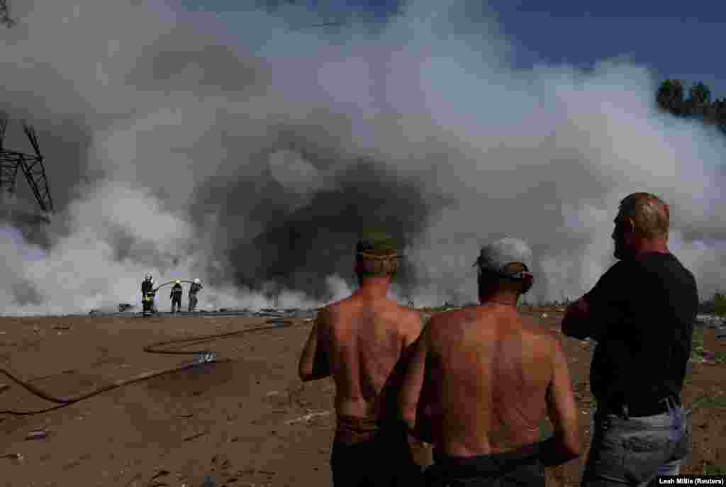 Onlookers watch as firefighters attempt to put out a fire attributed to Russian shelling in the Kharkiv region on June 20.