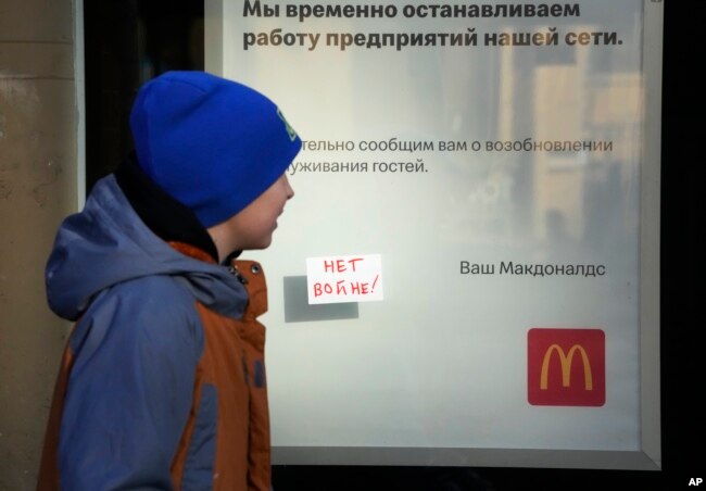 A boy walks past a "No War!" sign stuck to the window of a McDonald's with a restaurant closing notice in St. Petersburg on March 15.