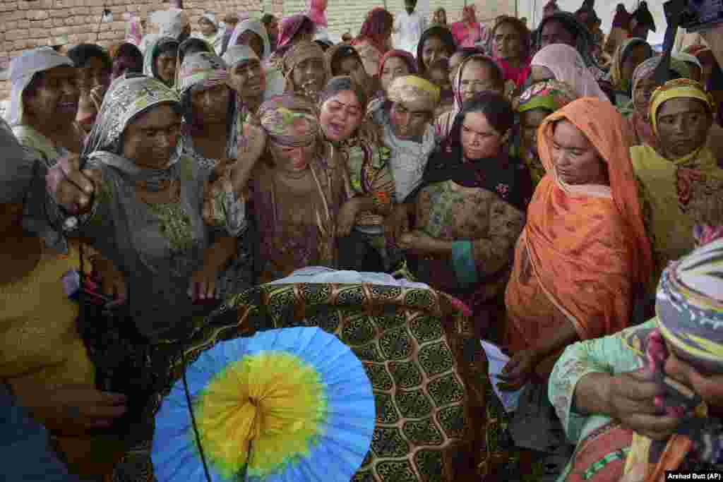 Women mourn around the body of a man who died when the roof of his house collapsed due to heavy rains, prior to his funeral on the outskirts of Quetta, Pakistan. At least six people, including women and children, were killed when the roofs of their homes collapsed in heavy rains lashing southwestern Pakistan and other parts of the country.