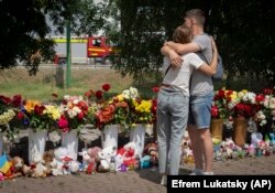 Люди кладуть квіти до меморіалу жертвам російської атаки в Кременчуку, 29 червня 2022 року
