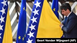 A member of protocol adjusts the Bosnian flag prior to arrivals at an EU summit in Brussels on June 23.