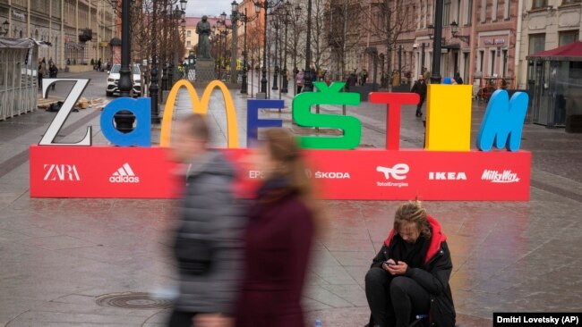 People walk past an installation that reads "Zamestim" (We Will Replace), assembled from the first letters of brands that left Russia in response to its invasion of Ukraine, in St. Petersburg in April.