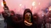 Roman Ratushniy, known for his civic and environmental activism, fires a flare at a political rally in Kyiv on February 2.