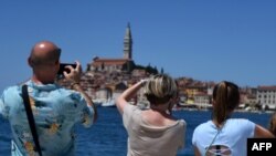 Turisták fotóznak az Isztriai-félsziget nyugati partján fekvő Rovinj városában 2022. június 11-én