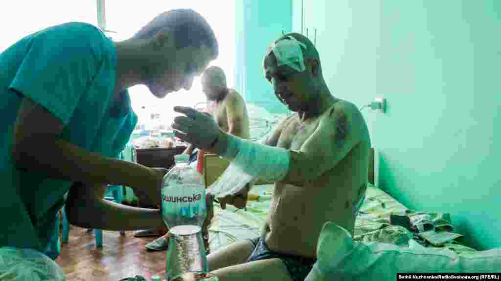 Медик перебинтовує руку 39-річному Миколі, який отримав поранення під час ракетного обстрілу ТРЦ &nbsp;&nbsp;