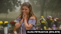 Egy nő sír 2022. június 28-án az áldozatok emlékére hozott virágok előtt a kremencsuki Amstor bevásárlóközpontnál, ahol legkevesebb tizennyolc embert öltek meg orosz rakéták