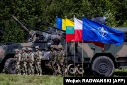 Польские (справа) и румынские (слева) у мобильного командного пункта Северо-Восточной многонациональной дивизии НАТО возле села Шиплишки, расположенного в так называемом Сувалкском коридоре ущелье, 7 июля 2022 года