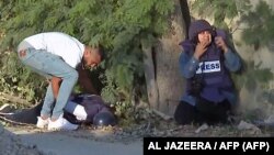 Nepoznati muškarac pokušava da podigne telo ubijene novinarke Širen Abu Akleh u izbegličkom logoru u Dženinu na okupiranoj Zapadnoj obali., 11. maj 2022. 