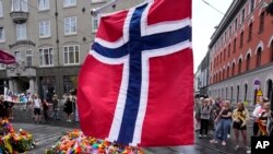 Norveška nacionalna zastava se vijori iznad cvijeća i zastave duginih boja postavljene na mjesto pucnjave u centru Osla, Norveška, u nedjelju, 26. juna 2022. 