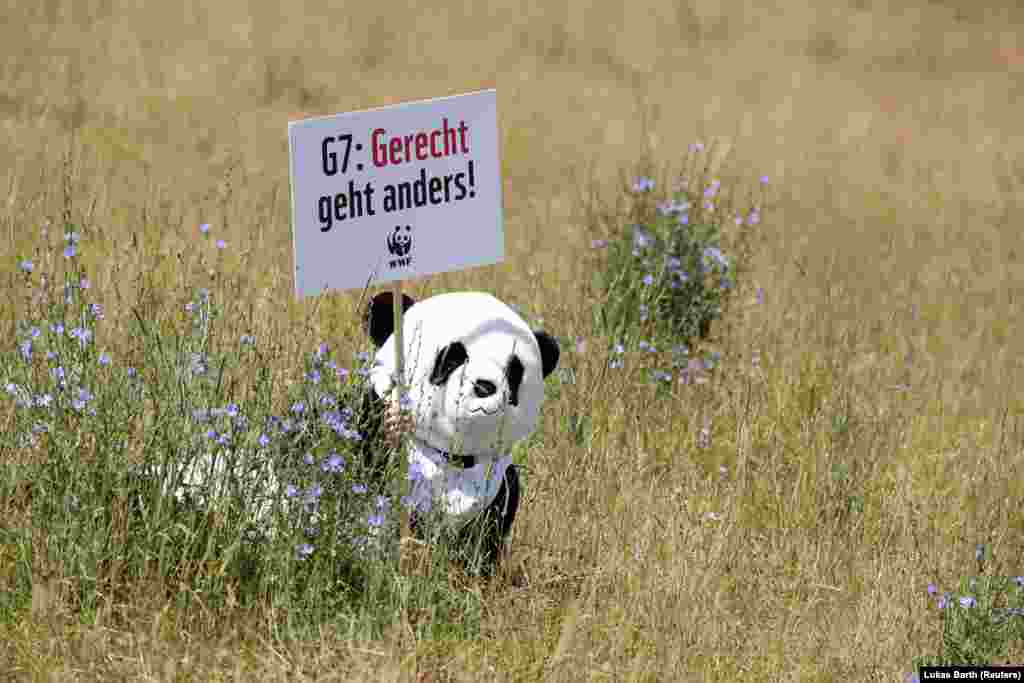 Demonstrant u kostimu medvjeda pande drži znak na kojem piše "G7: Pravda je drugačija" tokom protesta uoči samita lidera G7 u bavarskom alpskom odmaralištu Elmau Castle, u Minhenu, Njemačka, 25. juni 2022.