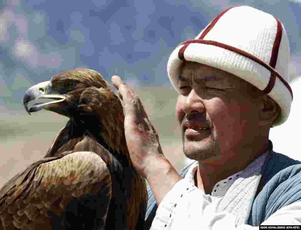 A Kyrgyz berkutchi, or eagle hunter, strokes his golden eagle.