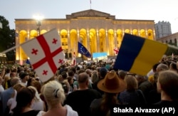 Manifestanți țin steagurile naționale ale Georgiei, UE și Ucrainei în timpul unui miting din fața clădirii Parlamentului din Tbilisi, Georgia, 20 iunie 2022, pentru a-și arăta sprijinul pentru candidatura țării la aderarea la UE.