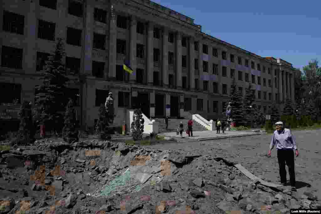 A bystander examines a 2.5-meter-deep crater left by a Russian missile strike in front of the Kharkiv State Zoo Veterinary Academy.