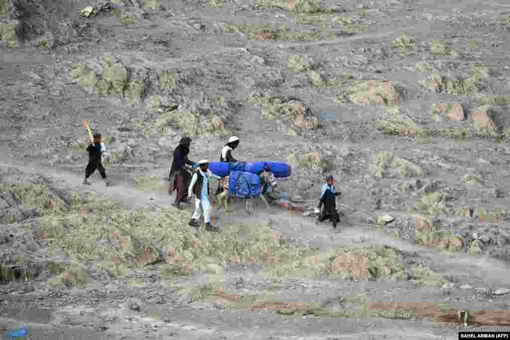 Volunteers carry aid received from the International Organization for Migration for people affected by the recent deadly earthquake in Khost Province.